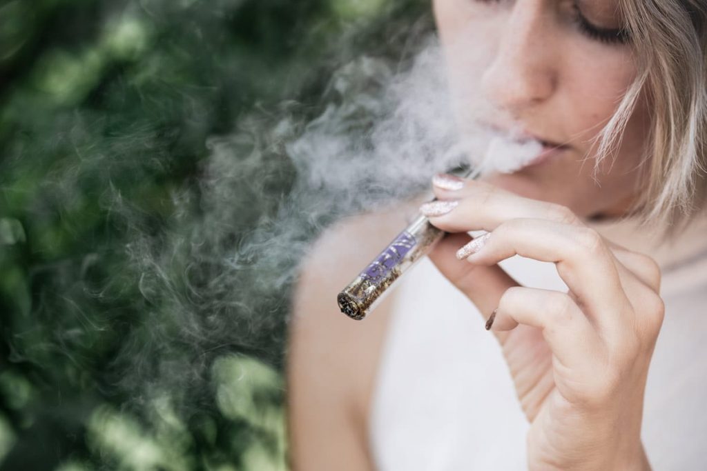 Young woman vaping marijuana.