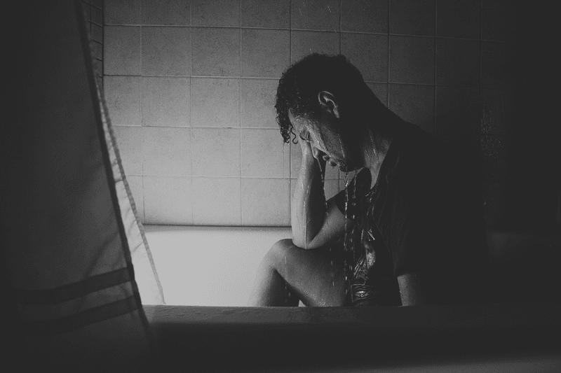 clothed man sitting in shower