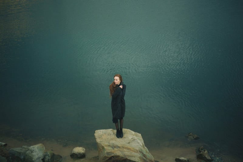 woman standing alone next to lake