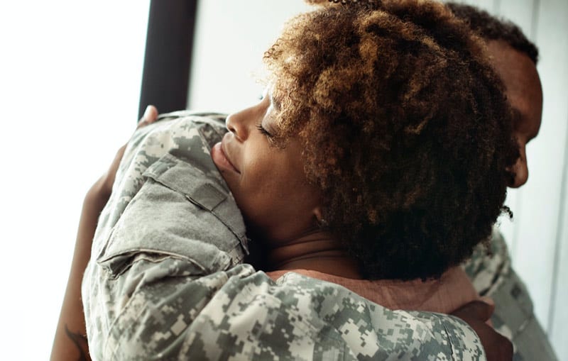 soldier and spouse embrace