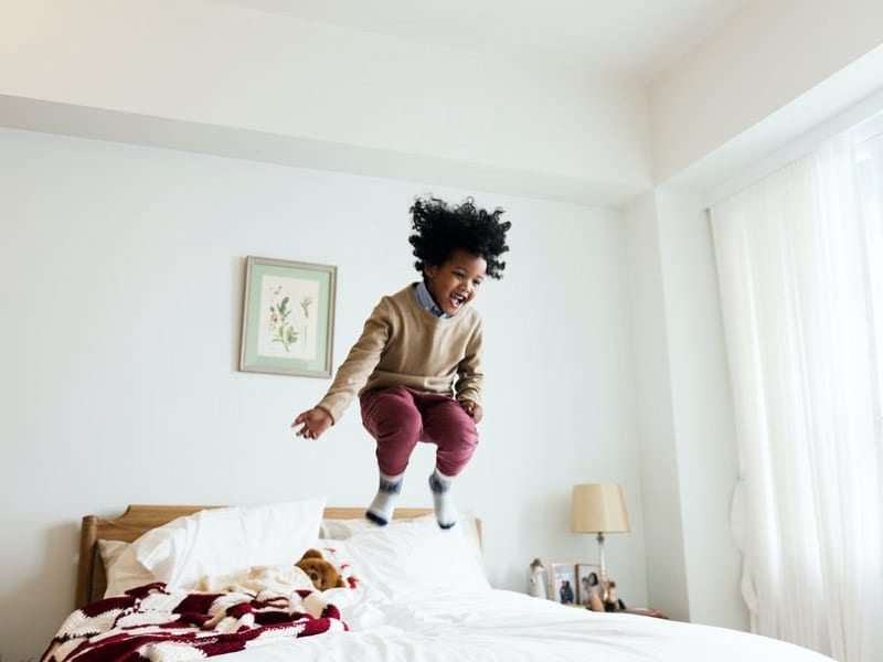 black child jumping on bed