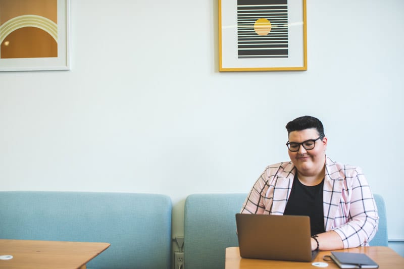 happy person using laptop on cushioned bench