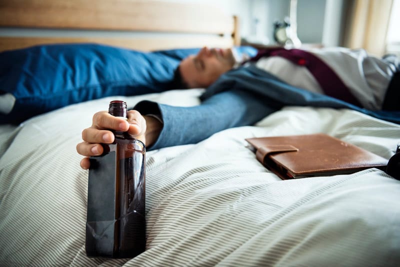 drunk businessman passed out on bed