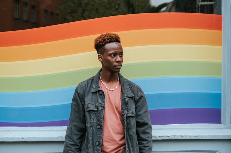 young black man in front of pride colors.