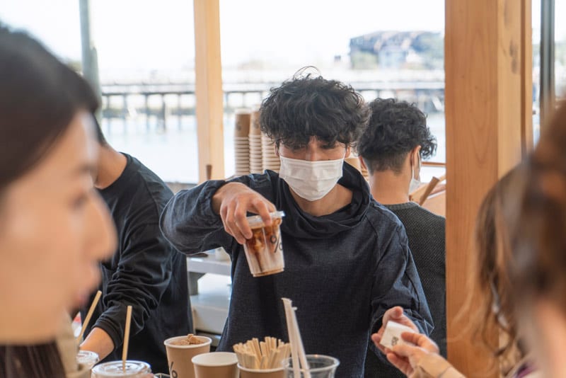 person in coffee shop wearing mask with to go cup
