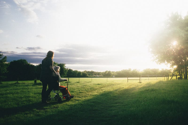 wheelchair user and caregiver in sunlit field