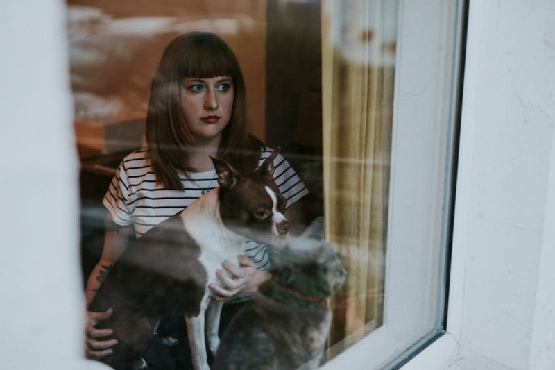 young woman with dog at window.