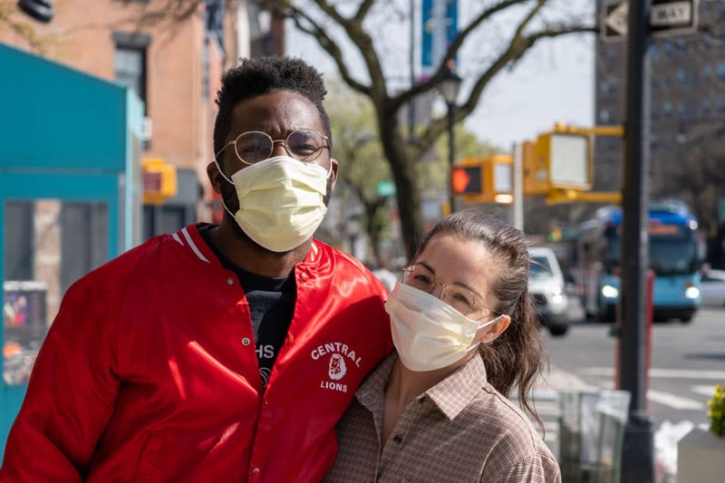 man and woman standing on sidewalk wearing medical masks