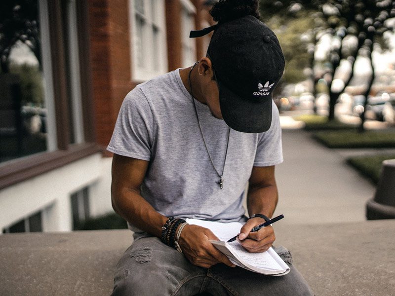young black man writing in journal