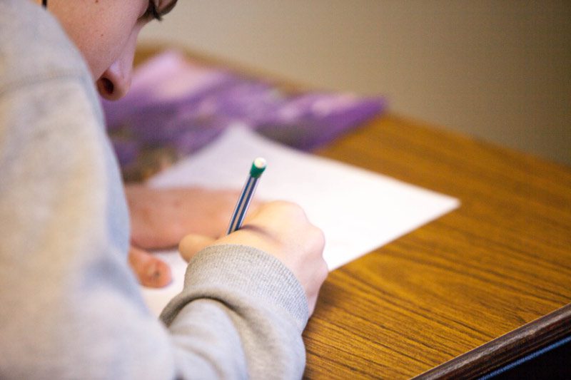 student at desk writing on paper