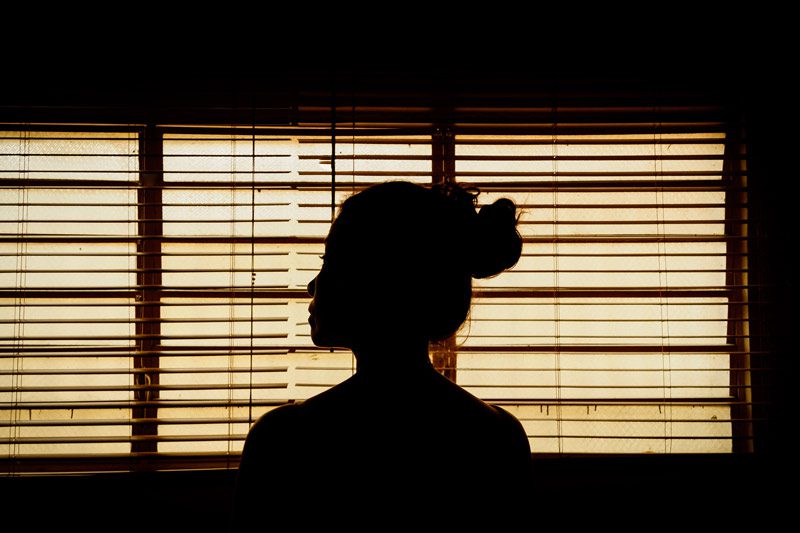 woman in front of window blinds