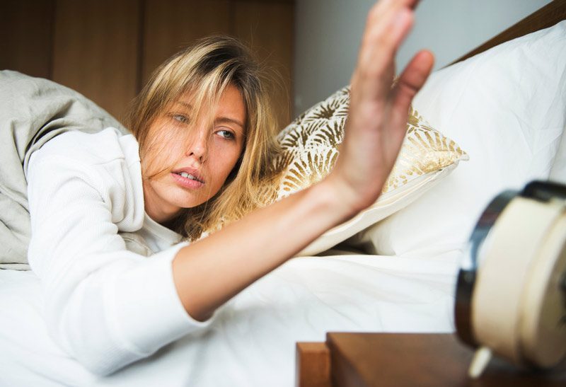 woman in bed with alarm clock.