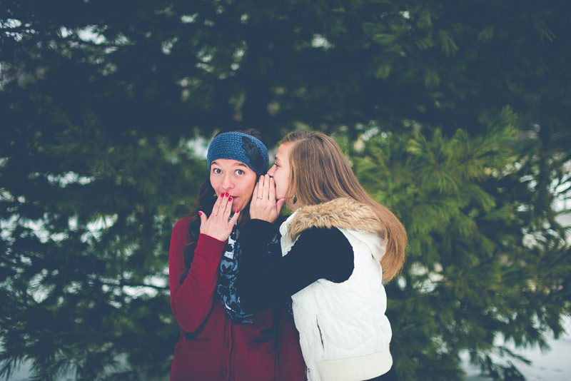 two young women share a secret