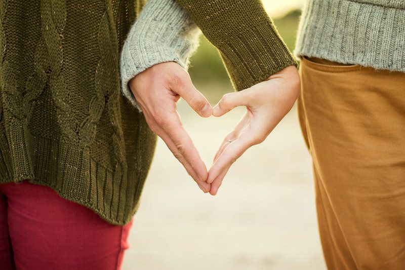 couple holding hands in heart sign