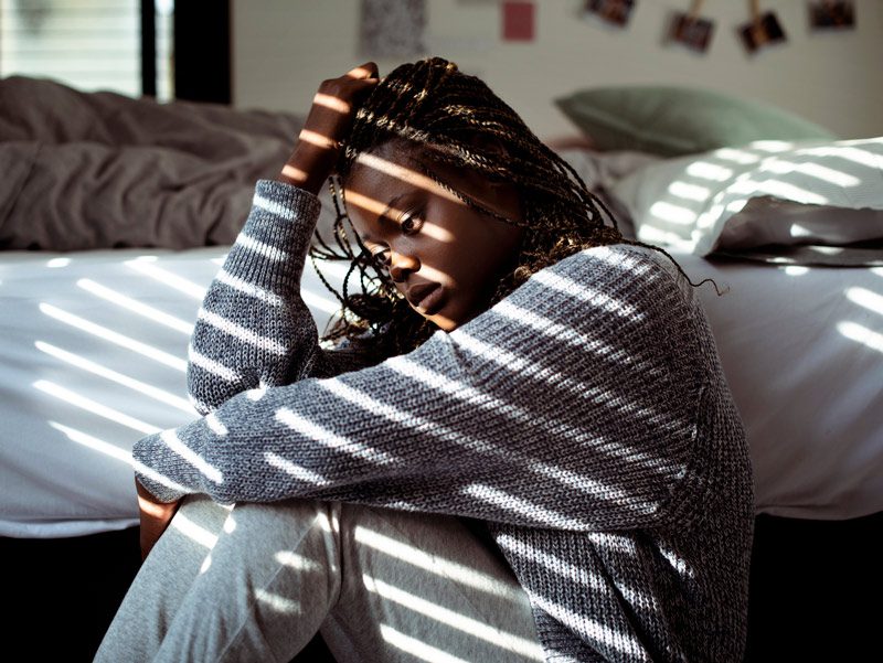 young African American woman sitting beside bed