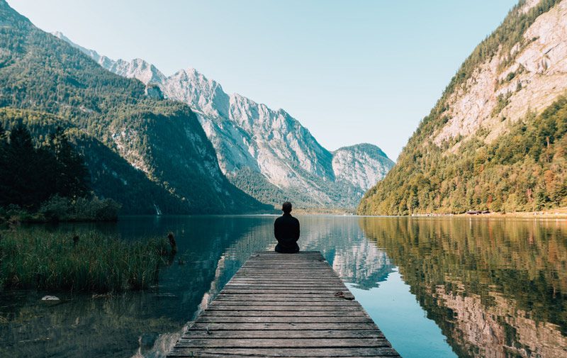 “man looking out on mountain lake