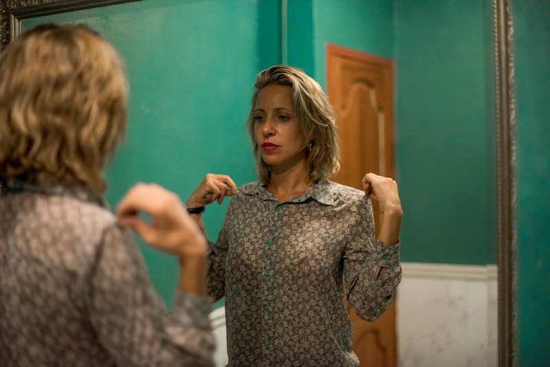 woman checking blouse in mirror.