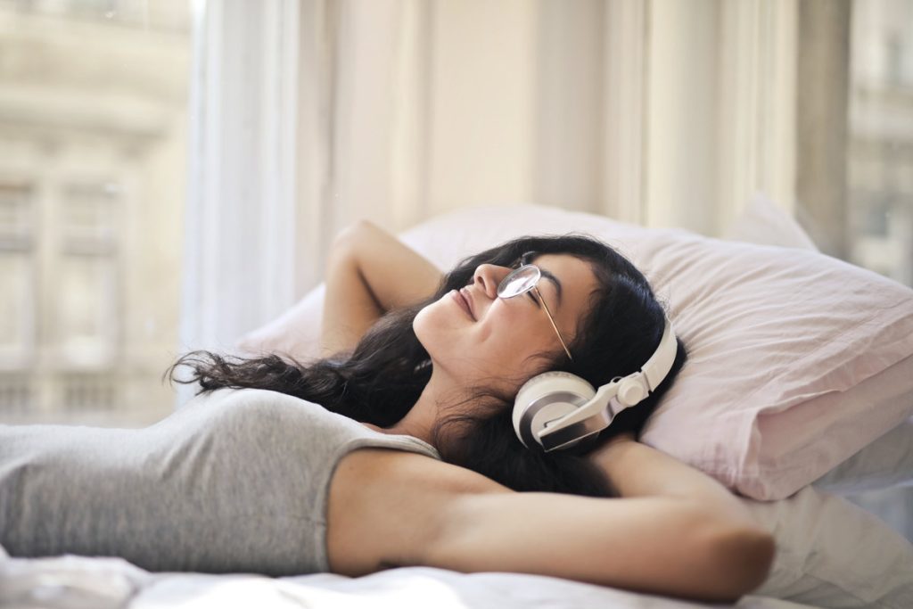 woman with headphones in bed