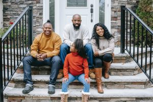 Black family sitting on doorstep.