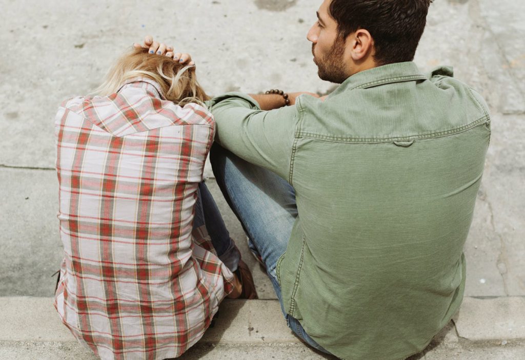 troubled couple sitting on curb
