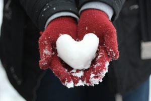 glove hands holding snow heart