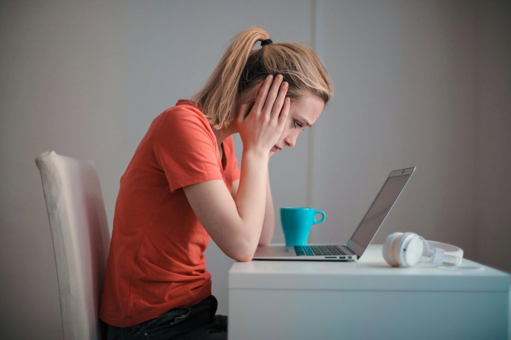 troubled woman staring at laptop.