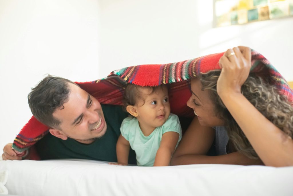 parents under blanket with small child