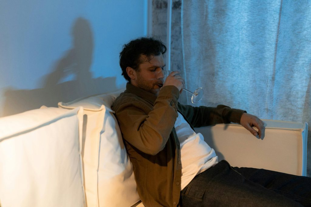 man on couch drinking wine.