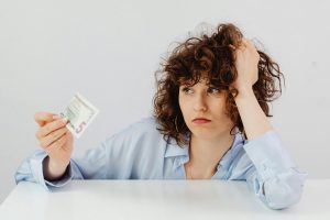 Worried woman holding a five dollar bill