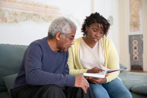 Young woman sitting beside older man with book.