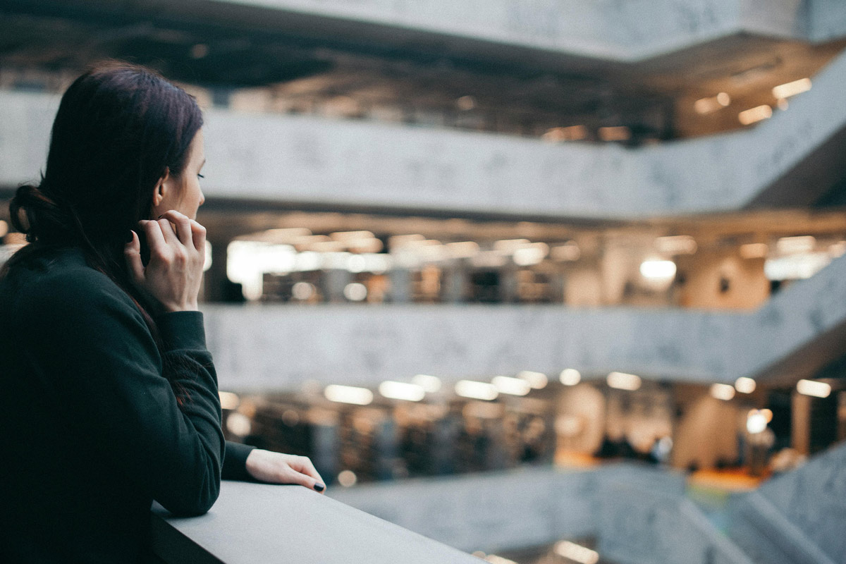 Lonely woman staring into the open concourse of a shopping mall