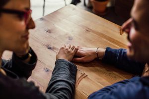 Close up of people holding hands across a table