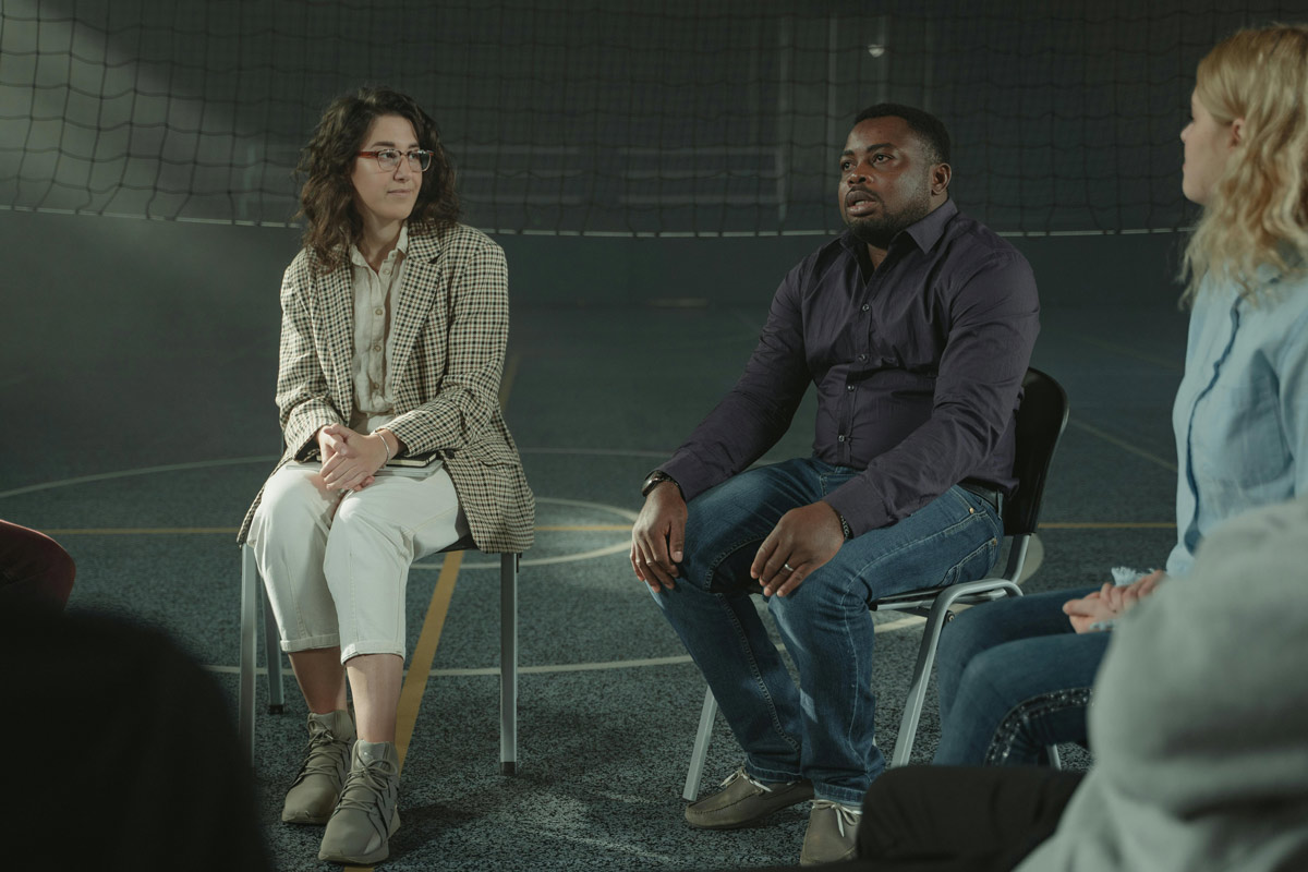 Three members of a peer support group sitting in a school gym