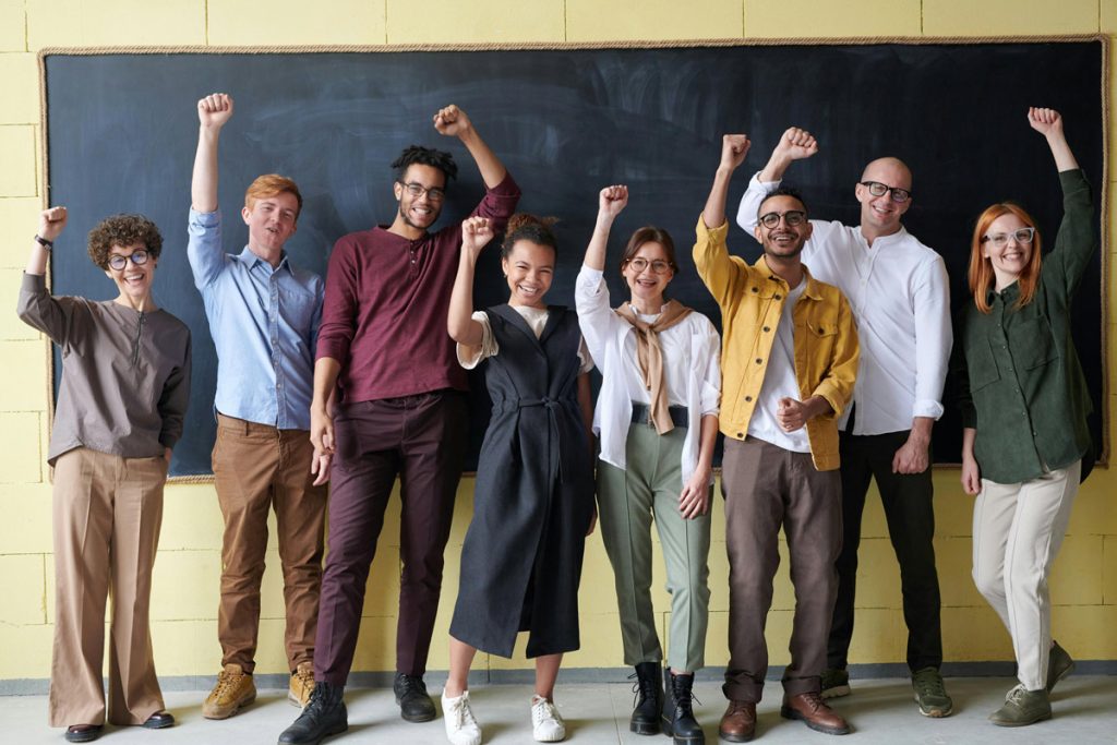 Diverse group of adults cheering in front of a blackboard