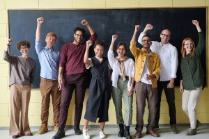 Diverse group of adults cheering in front of a blackboard