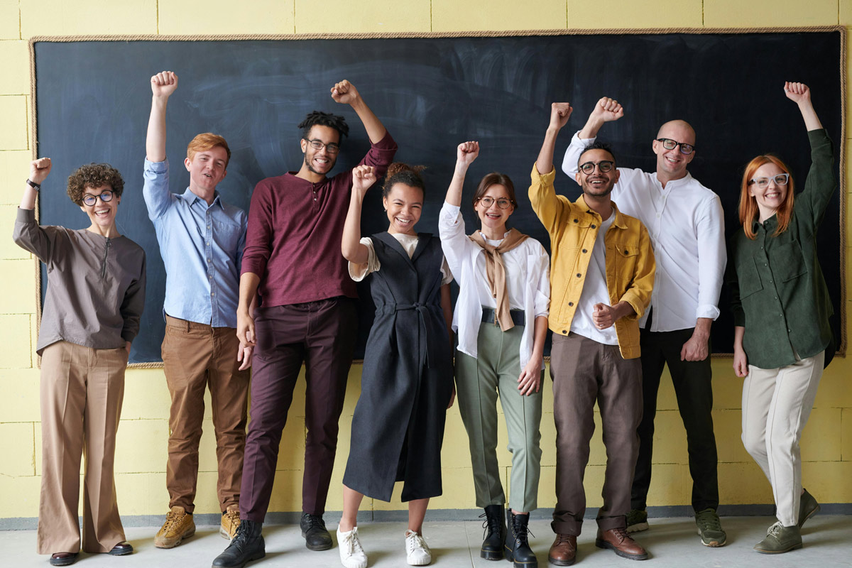 Diverse group of adults cheering in front of a blackboard