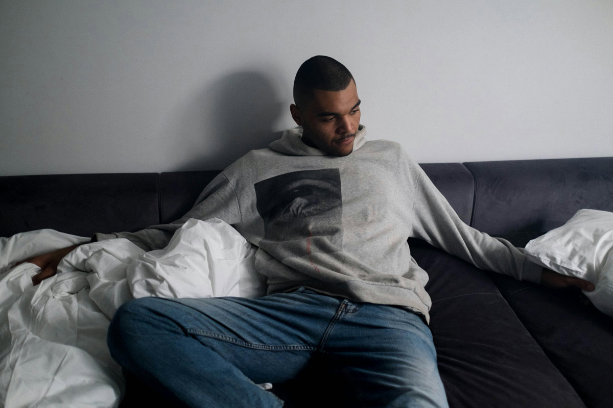 Worried man in sweatshirt and jeans sitting on couch