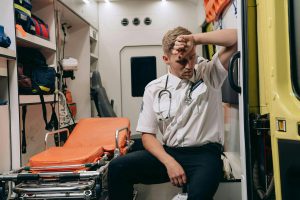Stressed out EMA worker sitting in back of ambulance.
