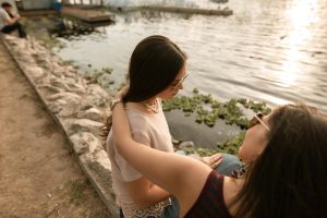 Mother and teen sitting on stone wall near the water.