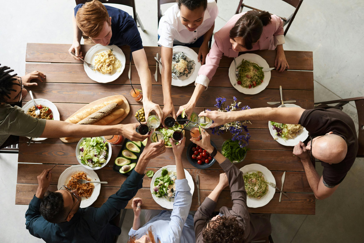 Group of friends enjoying a healthy meal around a wooden table.
