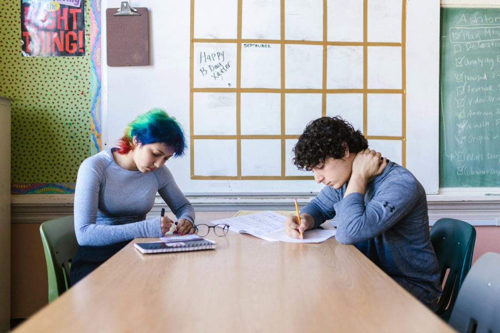 wo high school students sitting at table doing homework