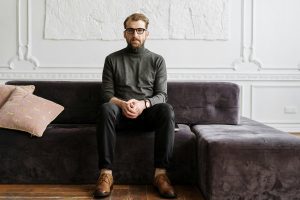 Bearded man with glasses sitting on purple couch