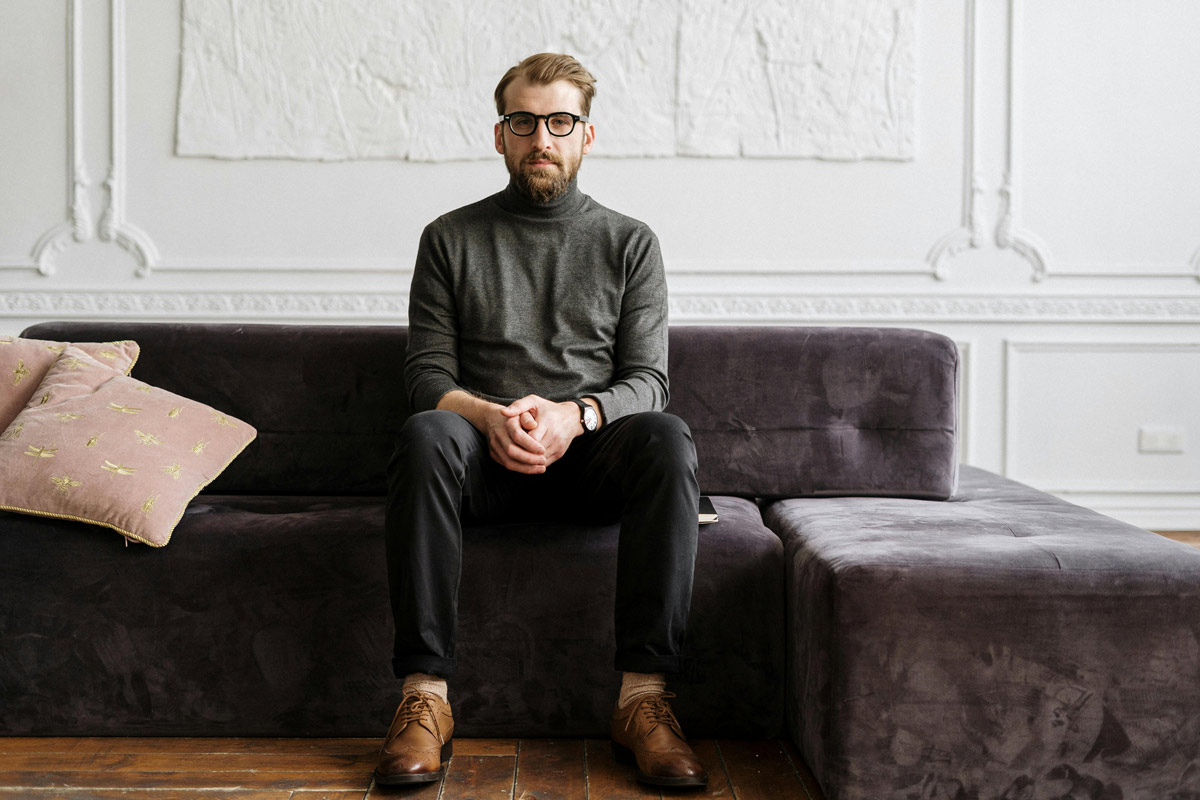 Bearded man with glasses sitting on purple couch