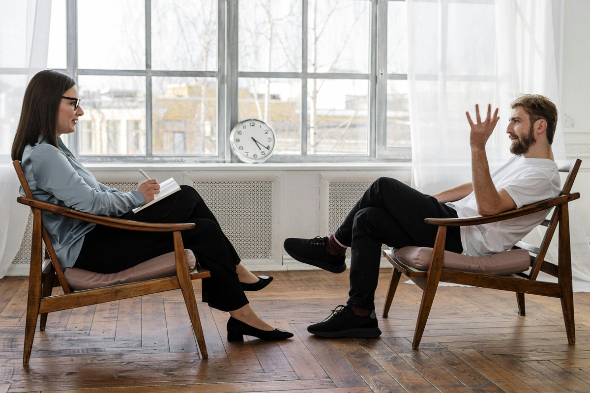 Therapist listening to a male client in a talk therapy session.