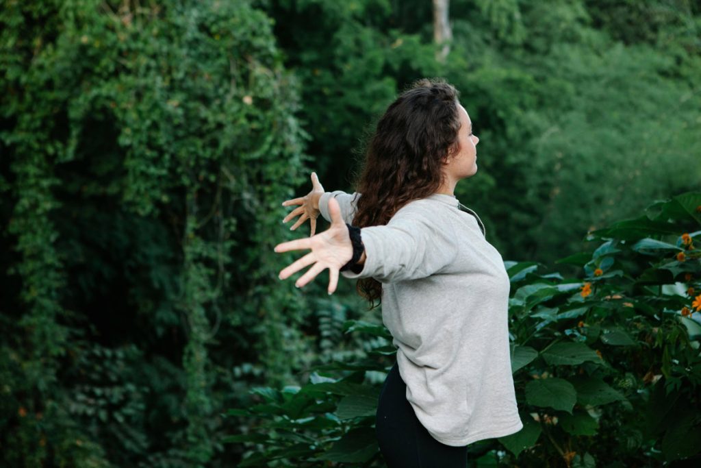 Young woman standing with arms outstretched in a field, symbolizing freedom, healing, and personal growth after anorexia recovery.