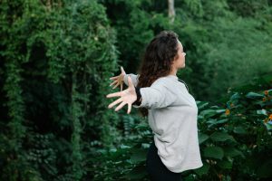 Young woman standing with arms outstretched in a field, symbolizing freedom, healing, and personal growth after anorexia recovery.