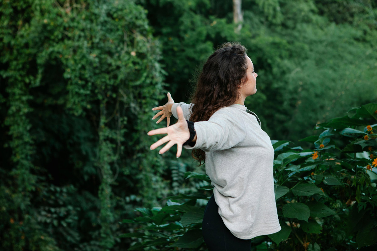 Young woman standing with arms outstretched in a field, symbolizing freedom, healing, and personal growth after anorexia recovery.