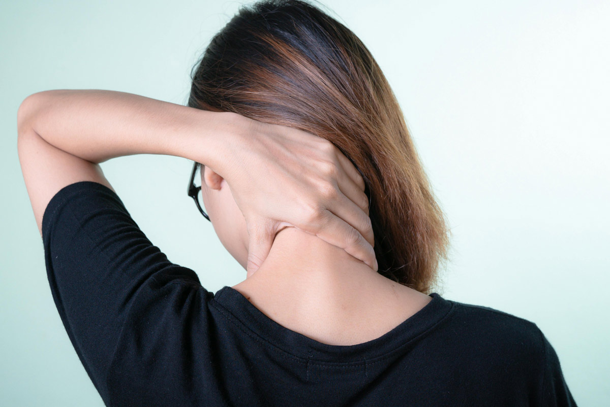 Young woman rubbing a sore neck from behind.