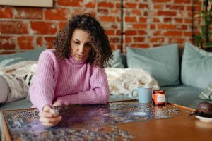 Woman in pink sweater engaging in a creative hobby, representing therapeutic activities for mental health and depression relief.
