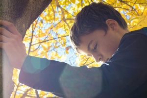 Young child sitting thoughtfully outdoors, representing the contemplative nature of childhood emotions and the importance of understanding children's mental health needs.